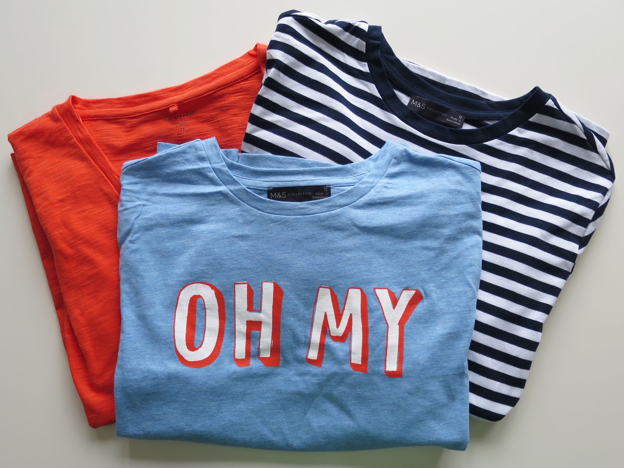 Marks and Spencer sustainable cotton tops - orange, stripey and blue with "oh my" written on the front